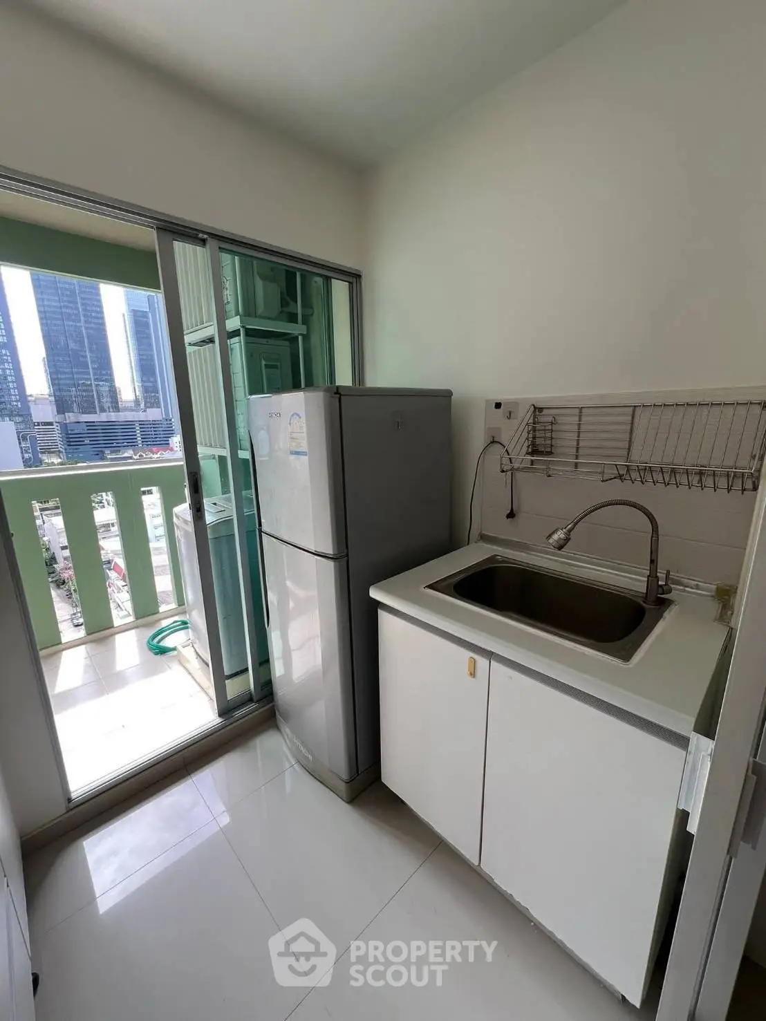 Modern kitchen with balcony view, featuring sleek cabinetry and stainless steel fridge.