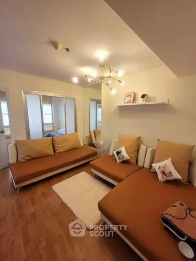 Cozy living room with modern lighting and stylish brown sofas in a well-lit apartment.