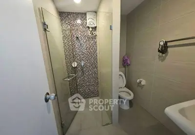 Modern bathroom with glass shower and mosaic tiles, featuring sleek fixtures and neutral tones.