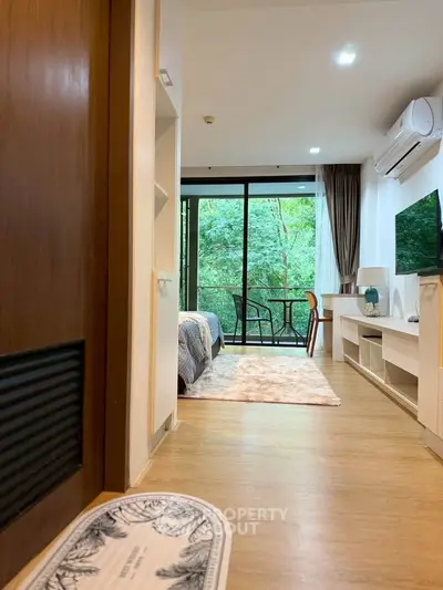Modern bedroom with balcony view, stylish decor, and natural light in a cozy apartment.