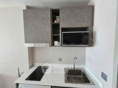 Modern kitchen with sleek cabinetry, built-in microwave, and electric cooktop in a compact layout.