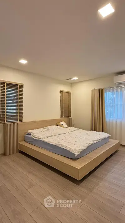 Spacious modern bedroom with wooden flooring and minimalist design