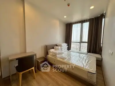 Modern bedroom with large windows and wooden flooring in a high-rise apartment.