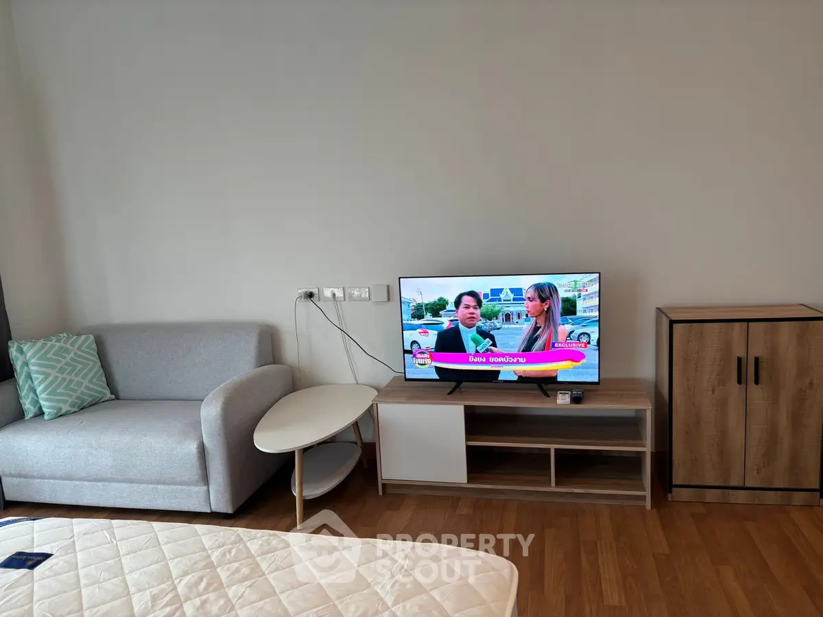 Modern living room with cozy sofa, TV, and stylish wooden cabinet on sleek wooden flooring.