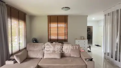 Spacious living room with modern beige sofa and natural light from large windows.