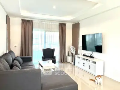 Spacious modern living room with sleek furniture and large TV, perfect for relaxation.