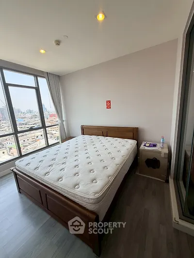 Spacious bedroom with city view, featuring a large window and modern furnishings.