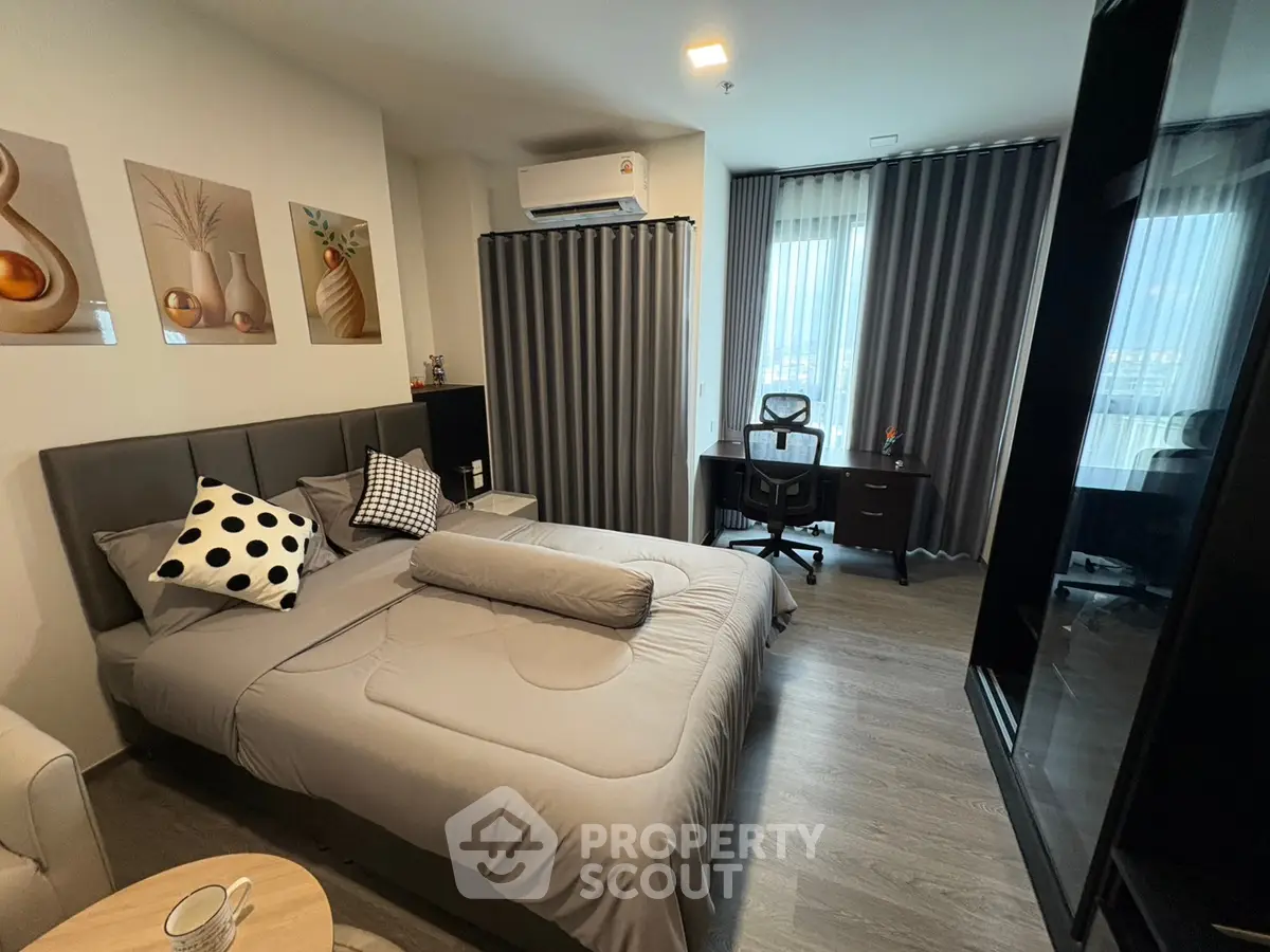 Modern bedroom with stylish decor and workspace, featuring large windows and contemporary furnishings.