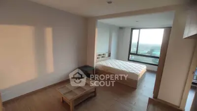 Spacious bedroom with large window and wooden flooring, offering a serene view.