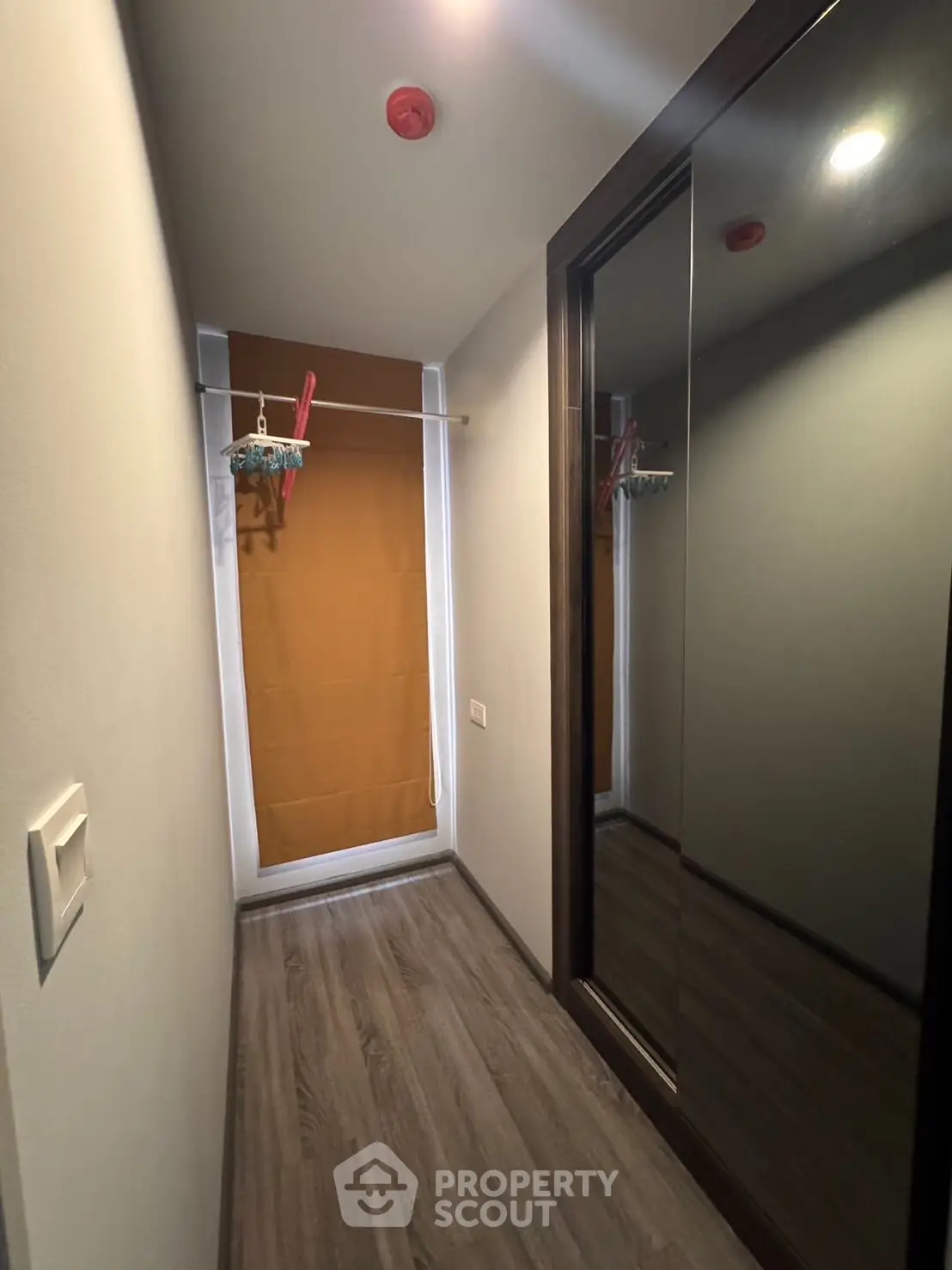 Compact storage room with mirrored wardrobe and wooden flooring