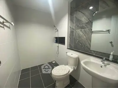 Modern bathroom with sleek design and elegant fixtures, featuring a spacious shower area and stylish tiling.