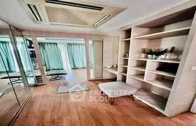 Spacious modern living room with wooden flooring and built-in shelves, perfect for stylish urban living.