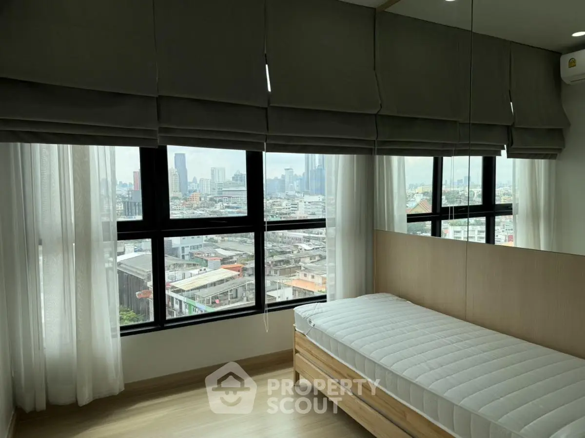 Modern bedroom with large windows offering stunning city views, featuring sleek design and abundant natural light.