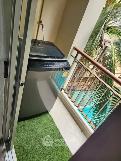 Charming balcony with washing machine and lush greenery view, perfect for urban living convenience.
