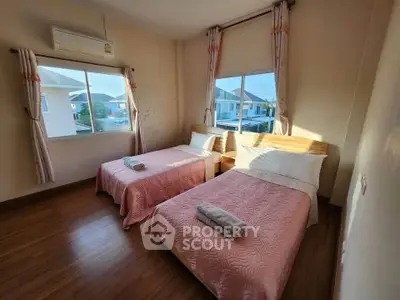 Cozy bedroom with twin beds and large windows offering natural light and neighborhood view.