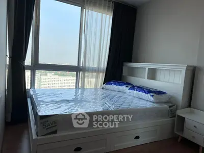 Modern bedroom with large window and city view, featuring a stylish bed and nightstand.