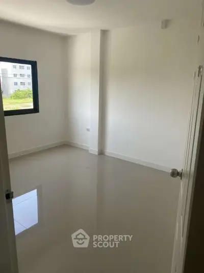 Spacious empty room with glossy tiled floor and large window view.