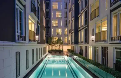 Luxurious apartment building with illuminated pool and elegant facade at dusk.