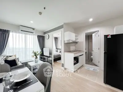 Modern open-plan apartment with stylish living area and kitchen, featuring large windows and elegant decor.