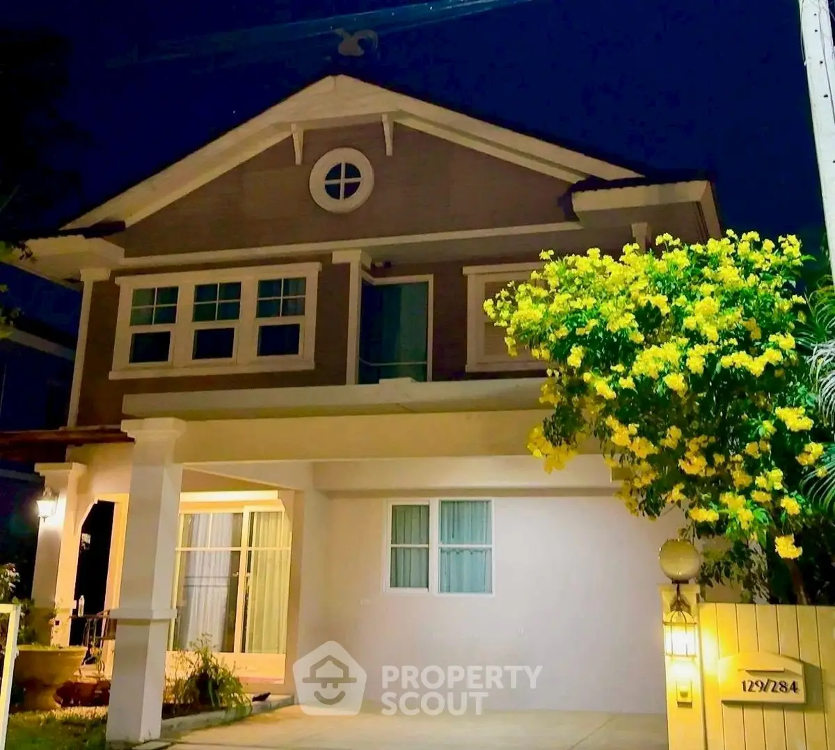 Charming two-story house with night lighting and lush garden