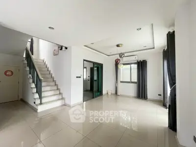Spacious modern living room with sleek tile flooring and elegant staircase