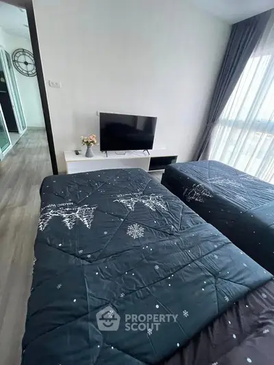 Modern bedroom with twin beds, TV, and large window offering natural light.