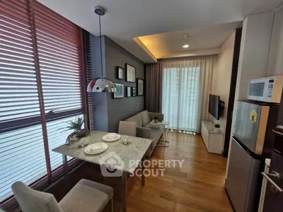 Modern living room with dining area, featuring sleek furniture and large windows for natural light.