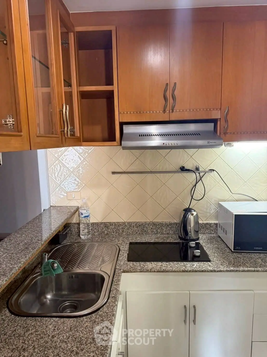 Modern kitchen with granite countertops, electric stove, and wooden cabinets