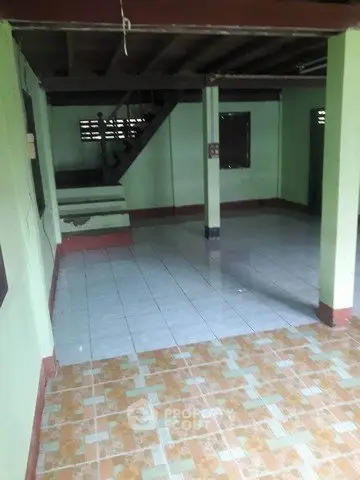 Spacious interior with tiled flooring and staircase, ideal for customization.