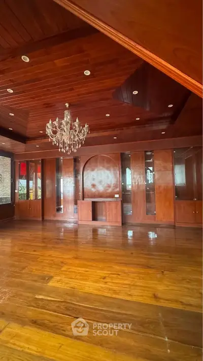 Luxurious wooden interior with elegant chandelier and built-in cabinets, perfect for a sophisticated living space.