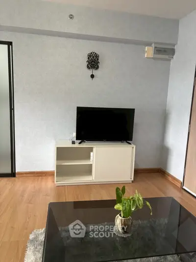 Modern living room with sleek TV stand and glass coffee table, perfect for cozy gatherings.