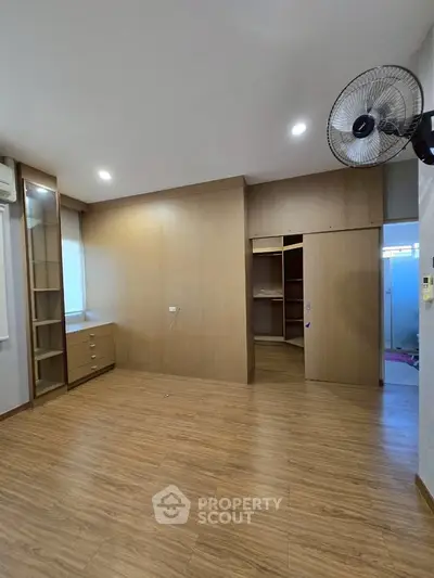 Spacious bedroom with wooden flooring and built-in wardrobe, ideal for modern living.