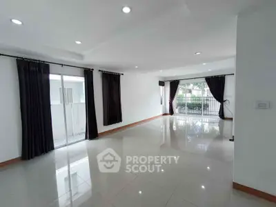 Spacious living room with large windows and glossy tiled floors, perfect for natural light and modern living.
