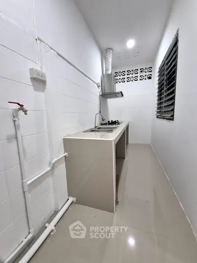 Modern minimalist kitchen with sleek countertops and gas stove in narrow layout