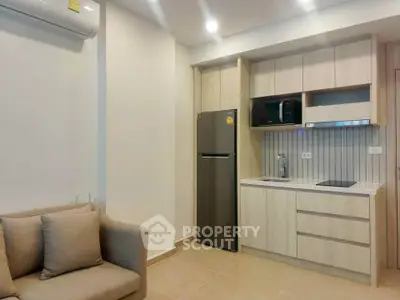 Modern compact kitchen with sleek cabinetry and cozy living area in a stylish apartment.
