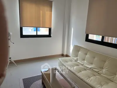 Modern living room with beige sofa and natural light through windows.
