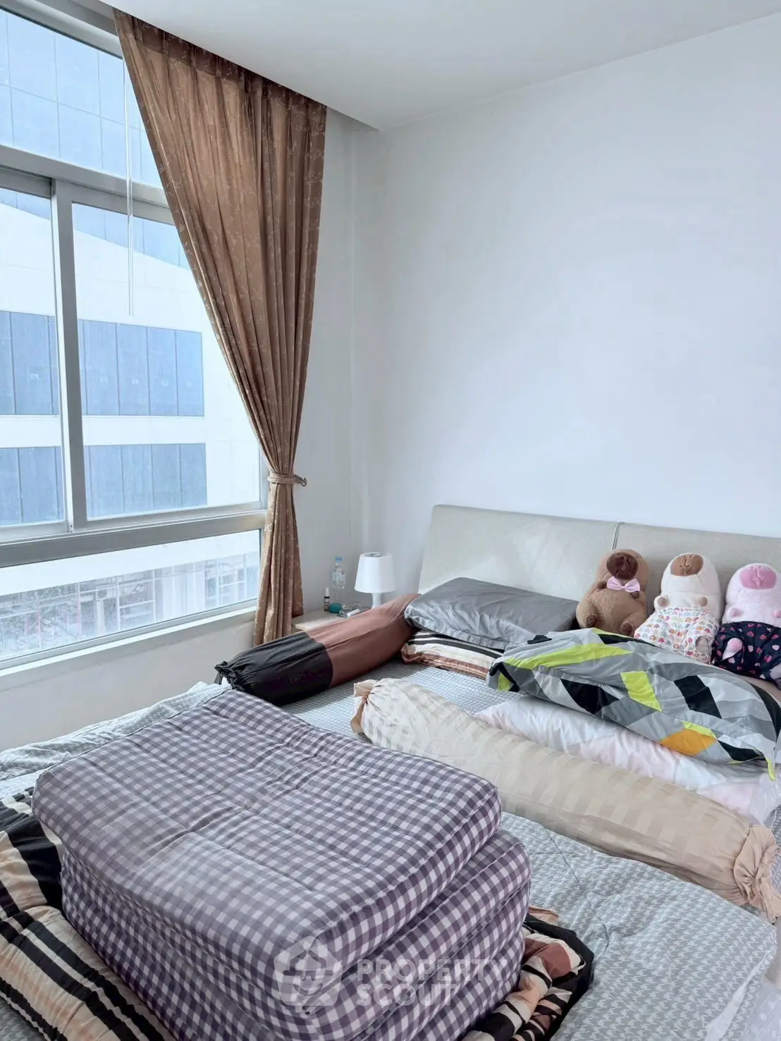 Cozy bedroom with large window and plush bedding in modern apartment