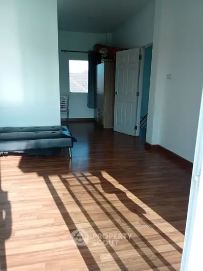 Spacious room with wooden flooring and natural light, perfect for versatile living space.