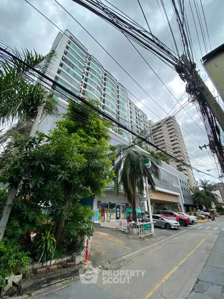 Modern high-rise building with lush greenery and street view, showcasing urban living.