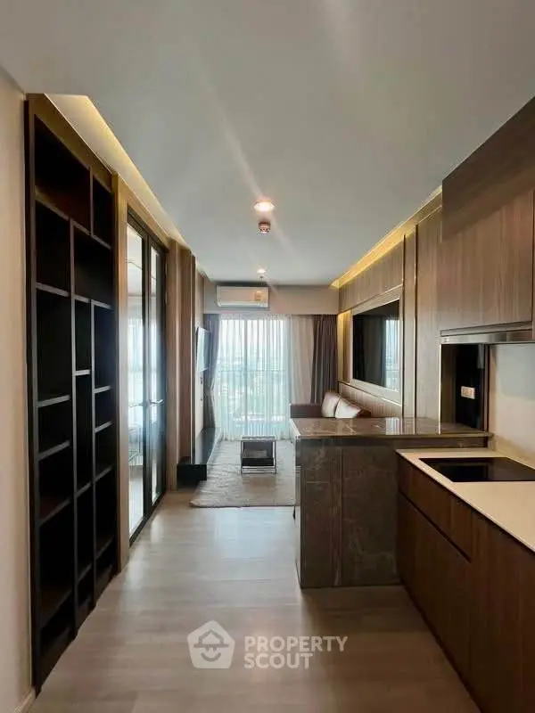 Modern open-plan living room with sleek kitchen and large windows offering natural light.