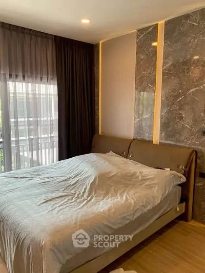 Luxurious bedroom with elegant marble accent wall and floor-to-ceiling windows for natural light.