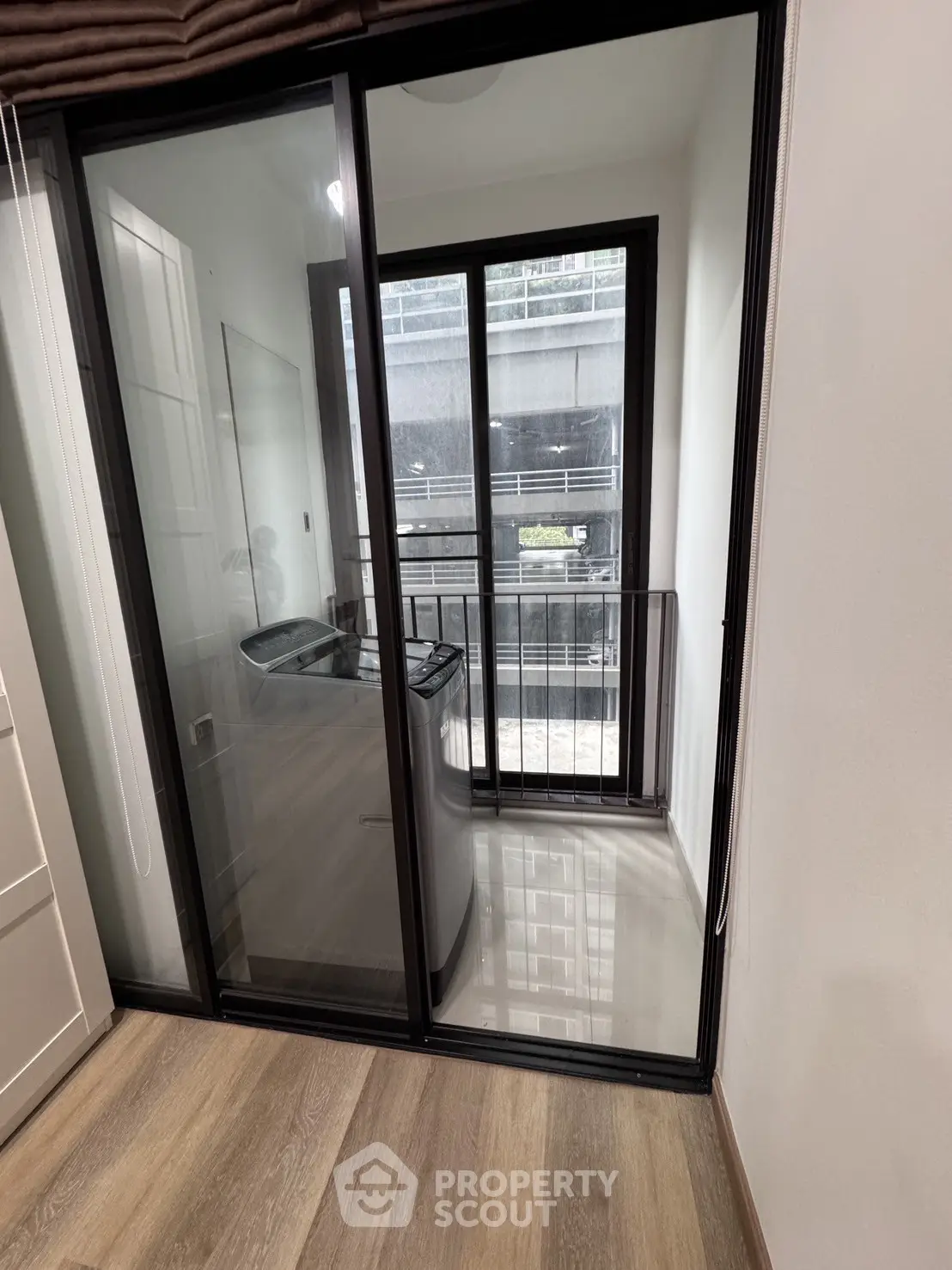 Compact laundry area with washing machine and sliding glass door in modern apartment.