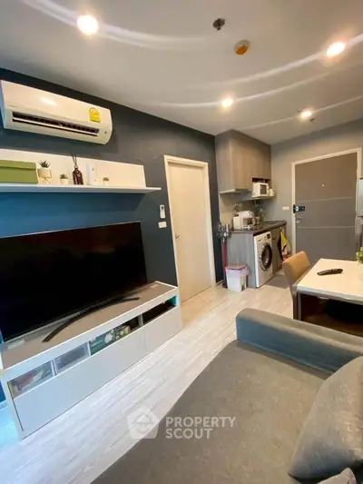 Modern living room with sleek furniture and integrated kitchen appliances in a cozy apartment.