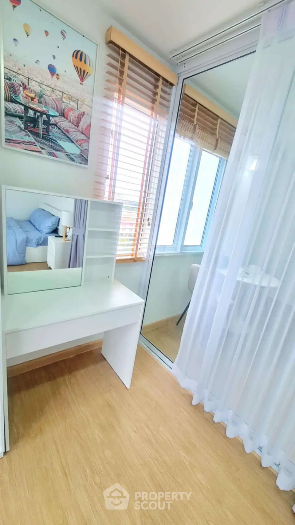 Bright bedroom with mirrored closet and wooden flooring, featuring a modern vanity and large windows.