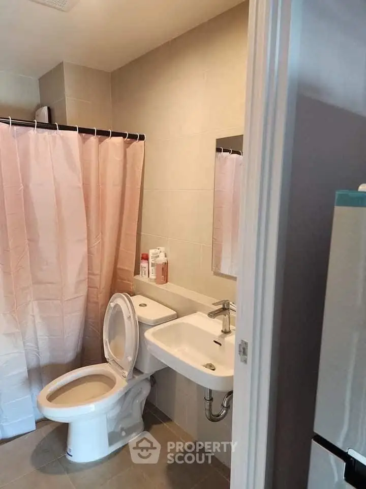 Modern bathroom with shower curtain and compact sink in a cozy apartment.