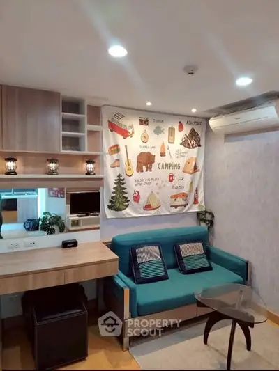 Cozy living room with modern decor and camping-themed wall art, featuring a teal sofa and stylish wooden furniture.