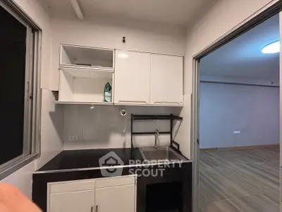 Modern kitchen with sleek black countertops and white cabinets, open layout to living area.