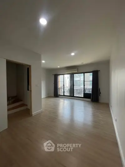 Spacious empty living room with large windows and wooden flooring