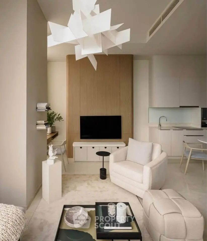 Modern living room with stylish furniture and open kitchen layout, featuring elegant decor and natural lighting.