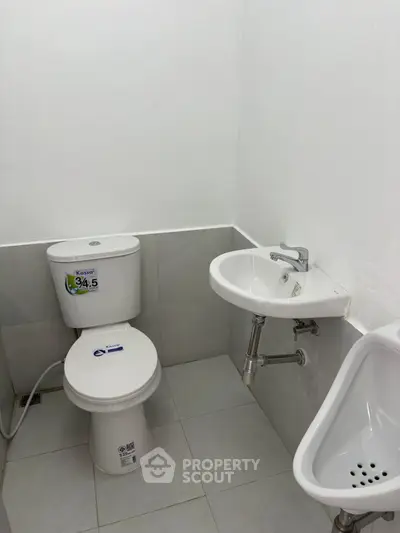 Compact bathroom with toilet, sink, and urinal in a minimalist design.